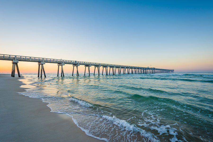 About Us - Pier Leading Out to Ocean at Sunset